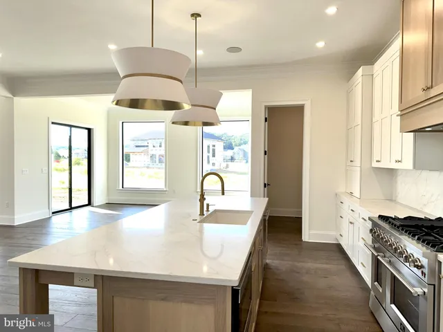 a kitchen with stainless steel appliances granite countertop a sink a stove and a wooden floors