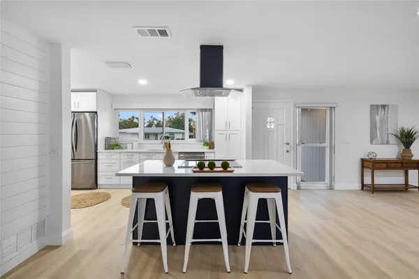 a kitchen with stainless steel appliances kitchen island a table chairs in it and wooden floors