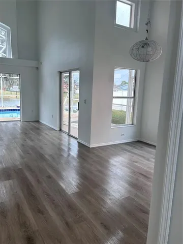 an empty room with wooden floor mirror and windows