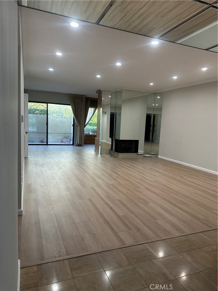 an empty room with wooden floor and natural light