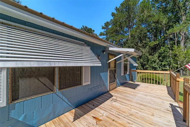 a view of a yard in front of a house with plants and large tree
