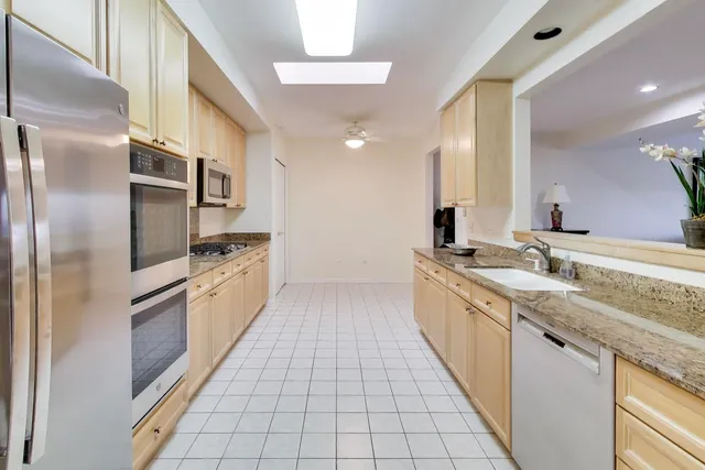 a large kitchen with stainless steel appliances granite countertop a refrigerator and a sink