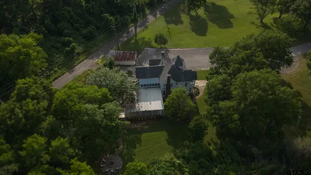 an aerial view of a house with pool outdoor space and trees all around