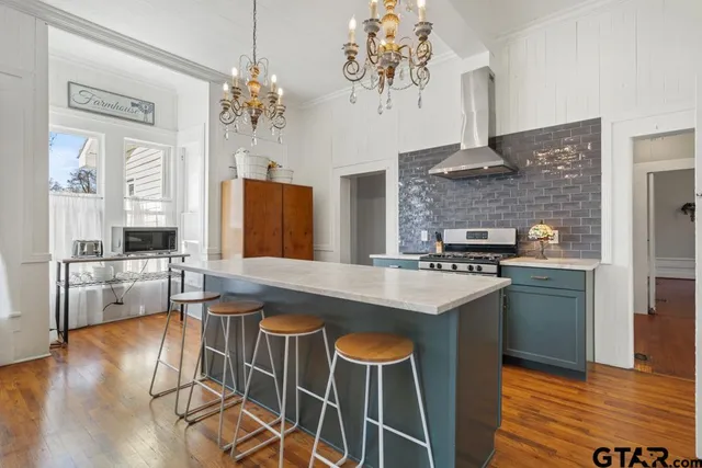 a kitchen with stainless steel appliances granite countertop a stove top oven a sink dishwasher and a refrigerator with wooden floor