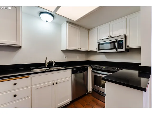 a kitchen with granite countertop white cabinets and a sink