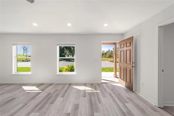 an empty room with wooden floor ceiling fan and windows