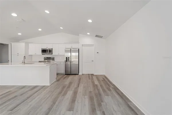 a large white kitchen with wooden floor and a sink
