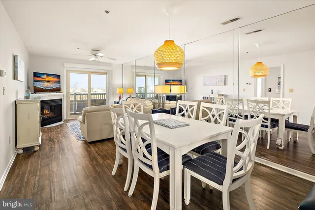 a view of a dining room with furniture one side kitchen view and wooden floor