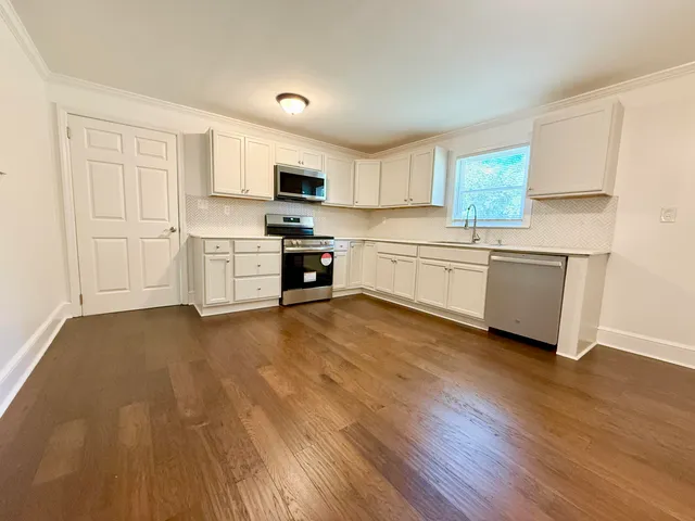 a large kitchen with cabinets wooden floor and stainless steel appliances
