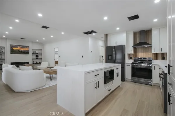 a kitchen with stainless steel appliances a stove a sink a refrigerator and white cabinets