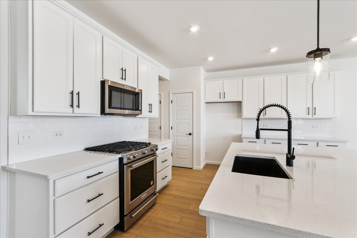 667 Switchgrass Way, Unit 62003 Bolingbrook, IL 60490 - Photo 13 of 33 a kitchen with white cabinets and appliances