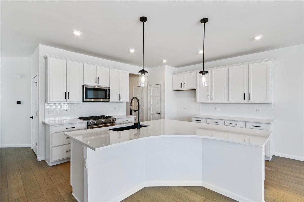 667 Switchgrass Way, Unit 62003 Bolingbrook, IL 60490 - Photo 14 of 33 a kitchen with stainless steel appliances a stove a sink a refrigerator a center island and cabinets
