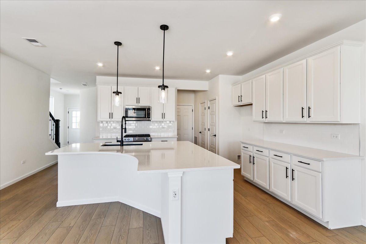 667 Switchgrass Way, Unit 62003 Bolingbrook, IL 60490 - Photo 15 of 33 a kitchen with stainless steel appliances kitchen island granite countertop a sink a stove and a refrigerator