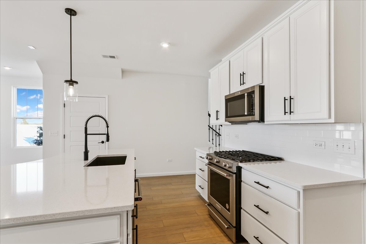 667 Switchgrass Way, Unit 62003 Bolingbrook, IL 60490 - Photo 17 of 33 a kitchen with stainless steel appliances granite countertop a stove a sink and a microwave