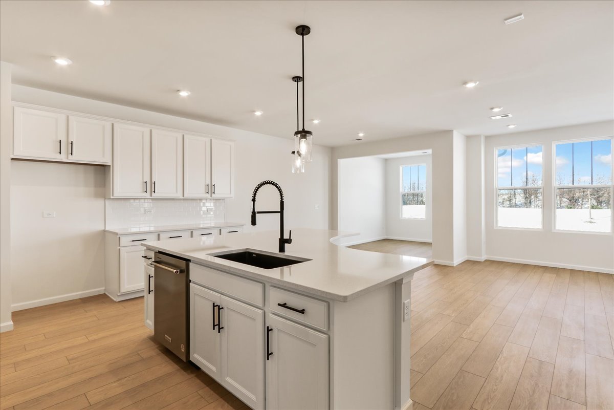 667 Switchgrass Way, Unit 62003 Bolingbrook, IL 60490 - Photo 18 of 33 a kitchen with white cabinets appliances and wooden floor