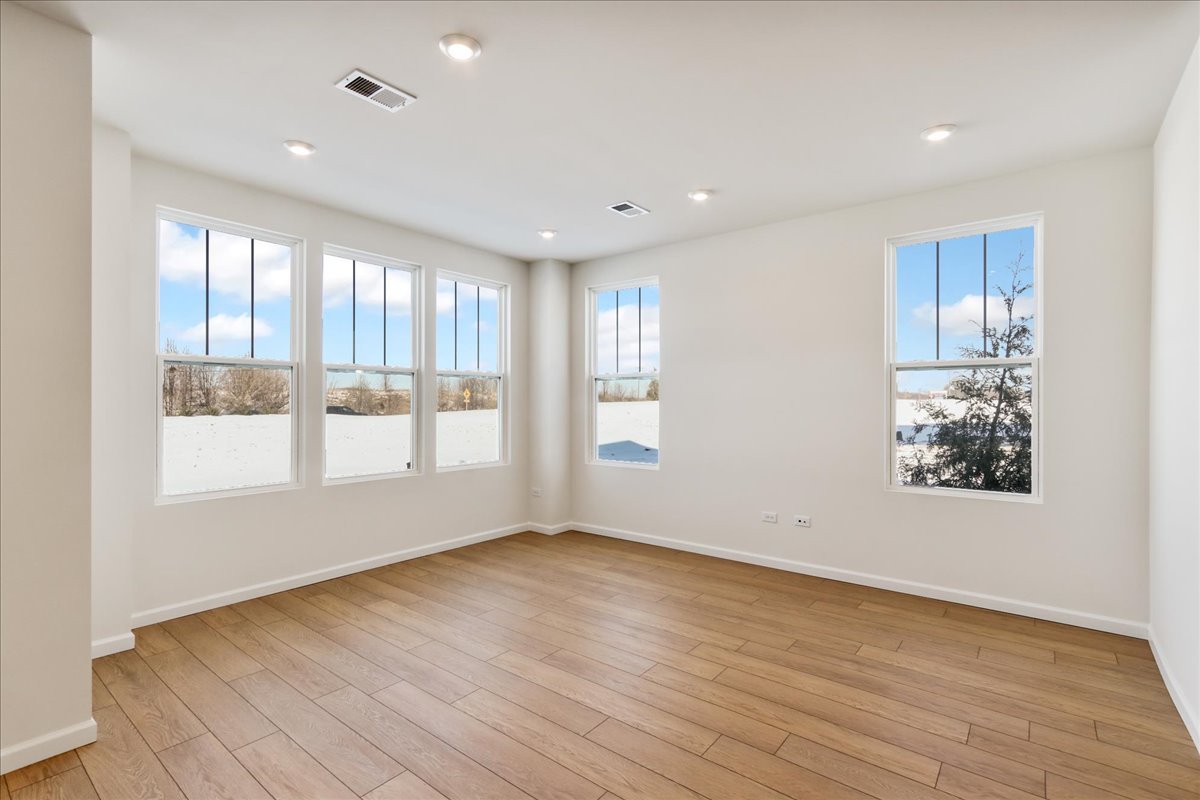667 Switchgrass Way, Unit 62003 Bolingbrook, IL 60490 - Photo 6 of 33 a view of an empty room with a window and wooden floor