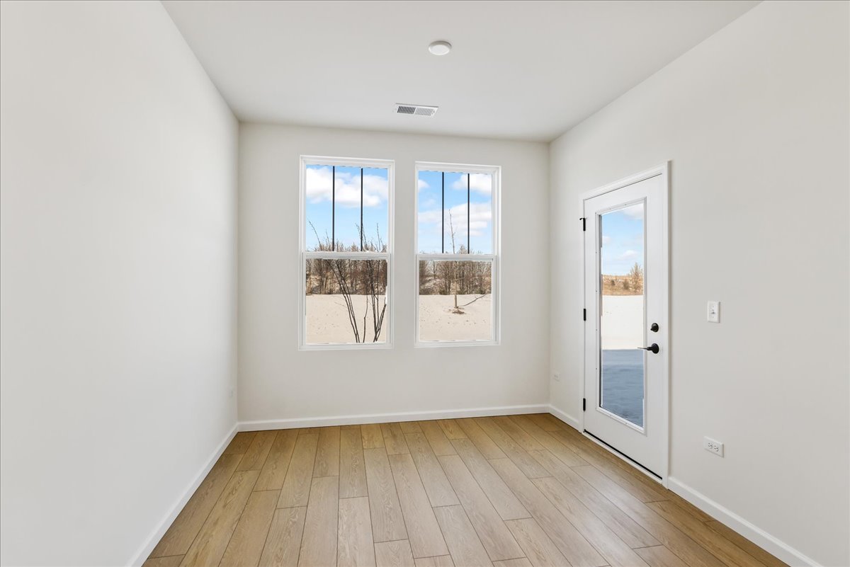 667 Switchgrass Way, Unit 62003 Bolingbrook, IL 60490 - Photo 8 of 33 an empty room with wooden floor and windows