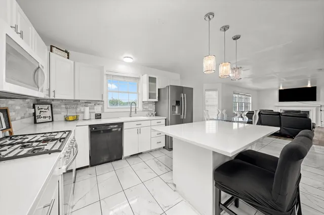 a large white kitchen with a stove a sink dishwasher and a refrigerator with wooden floor