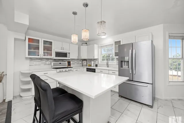 a kitchen with stainless steel appliances a refrigerator a stove a sink a dining table and chairs