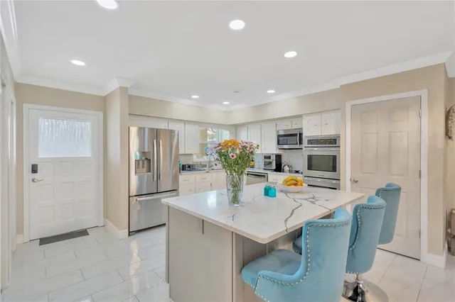 a kitchen with stainless steel appliances a dining table chairs and refrigerator