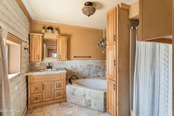 a bathroom with a granite countertop sink a mirror a bathtub and shower