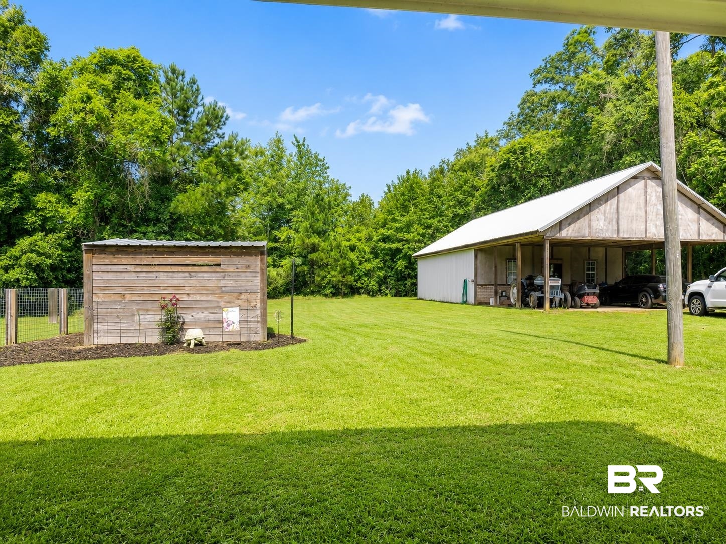 21733 Sedlack Road Silverhill, AL 36576 - Photo 7 of 22 Expansive lawn area featuring a large outbuilding with a covered carport, and a separate fenced enclosure with a wood-sided shed