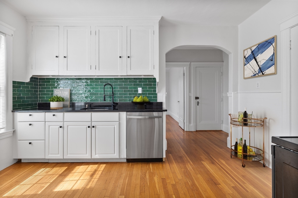 a kitchen with stainless steel appliances white cabinets and wooden floors