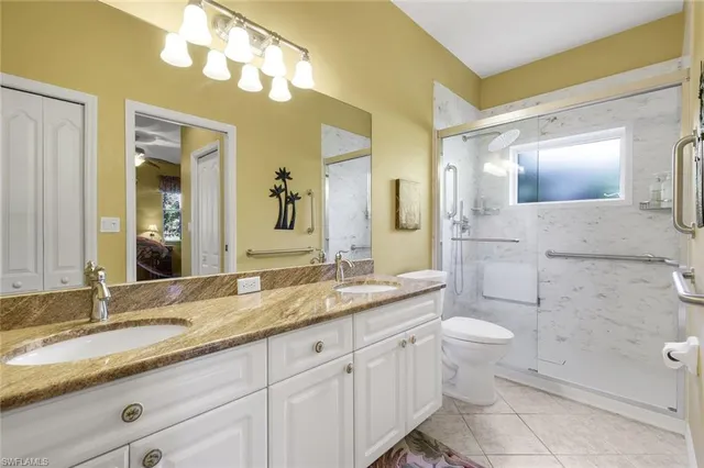 a bathroom with a granite countertop double vanity sink mirror and toilet