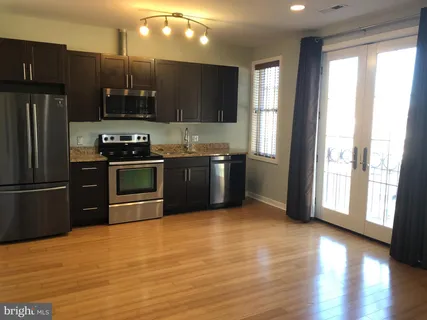 a kitchen with stainless steel appliances granite countertop a refrigerator a sink a stove with wooden floors and cabinets