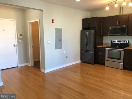 a view of kitchen with stainless steel appliances wooden floor and staircase