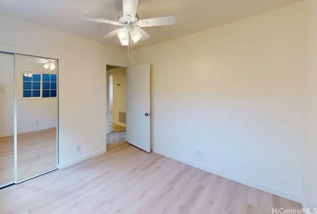 an empty room with closet and a ceiling fan