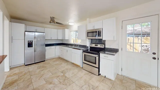 a kitchen with granite countertop a refrigerator and a stove top oven