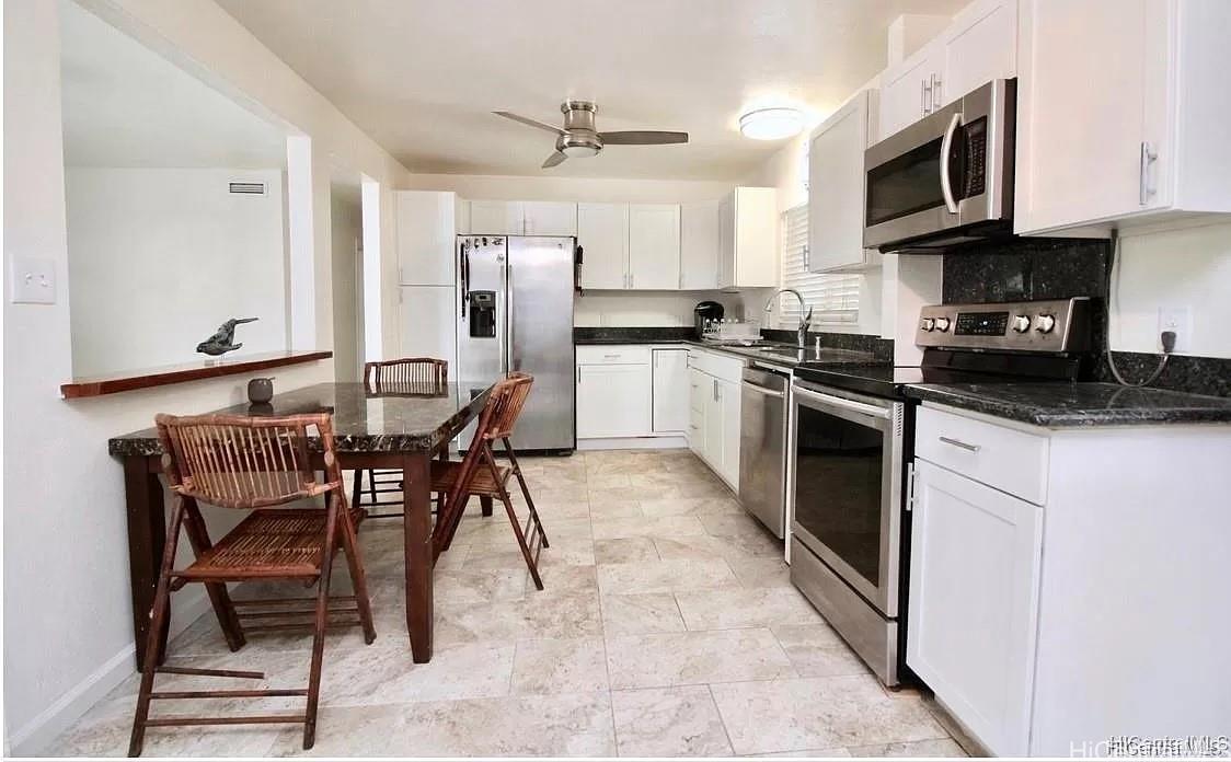 85-059 Waianae Valley Road Waianae, HI 96792 - Photo 6 of 20 a kitchen with stainless steel appliances granite countertop a stove top oven a sink a dining table and chairs