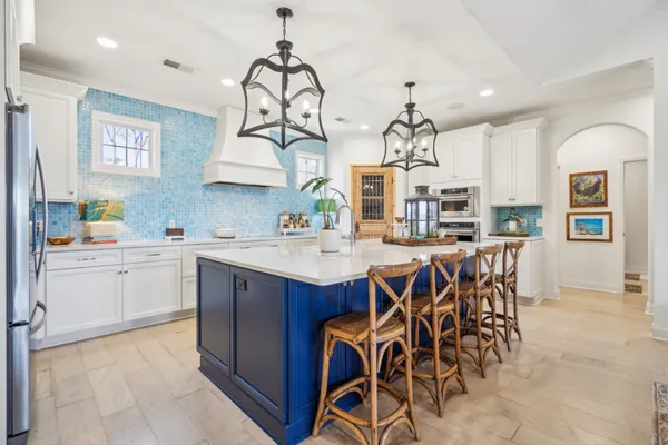 a kitchen with a dining table chairs sink and white cabinets