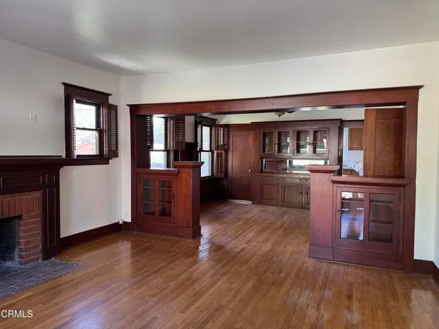 a view of a living room with wooden floor and a kitchen