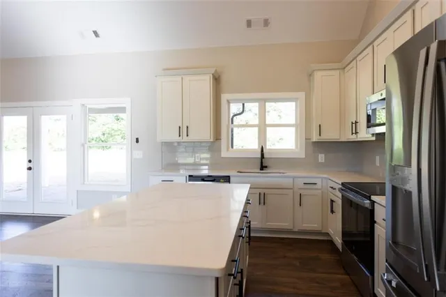a kitchen with a sink a window a refrigerator and white cabinets