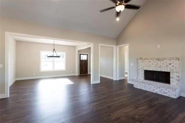 a view of an empty room with wooden floor fireplace and a window