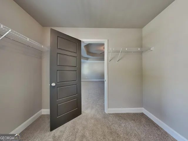 an empty room with chandelier fan and windows