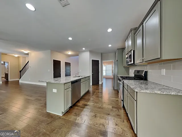 a large kitchen with stainless steel appliances kitchen island granite countertop a large counter top and a stove top oven