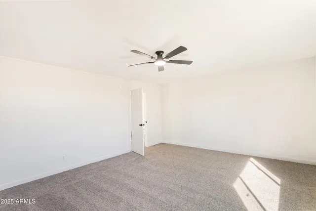 an empty room with a ceiling fan and a window