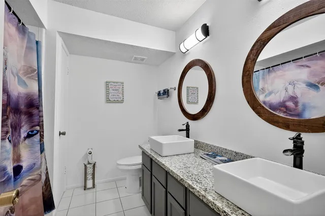 a bathroom with a granite countertop toilet a sink and a mirror