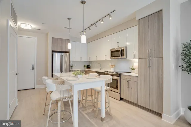 a kitchen with stainless steel appliances kitchen island a table chairs refrigerator and microwave