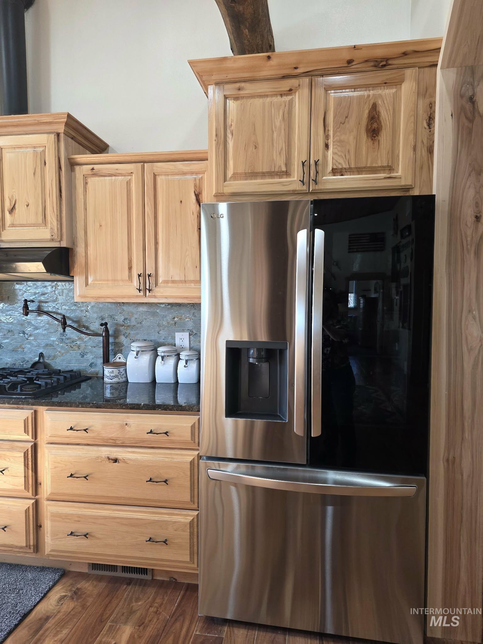 809 River Pointe Lane Lenore, ID 83541 - Photo 19 of 43 Kitchen featuring stainless steel fridge, dark stone countertops, light wood finish cabinets, extractor fan, and dark wood-style flooring