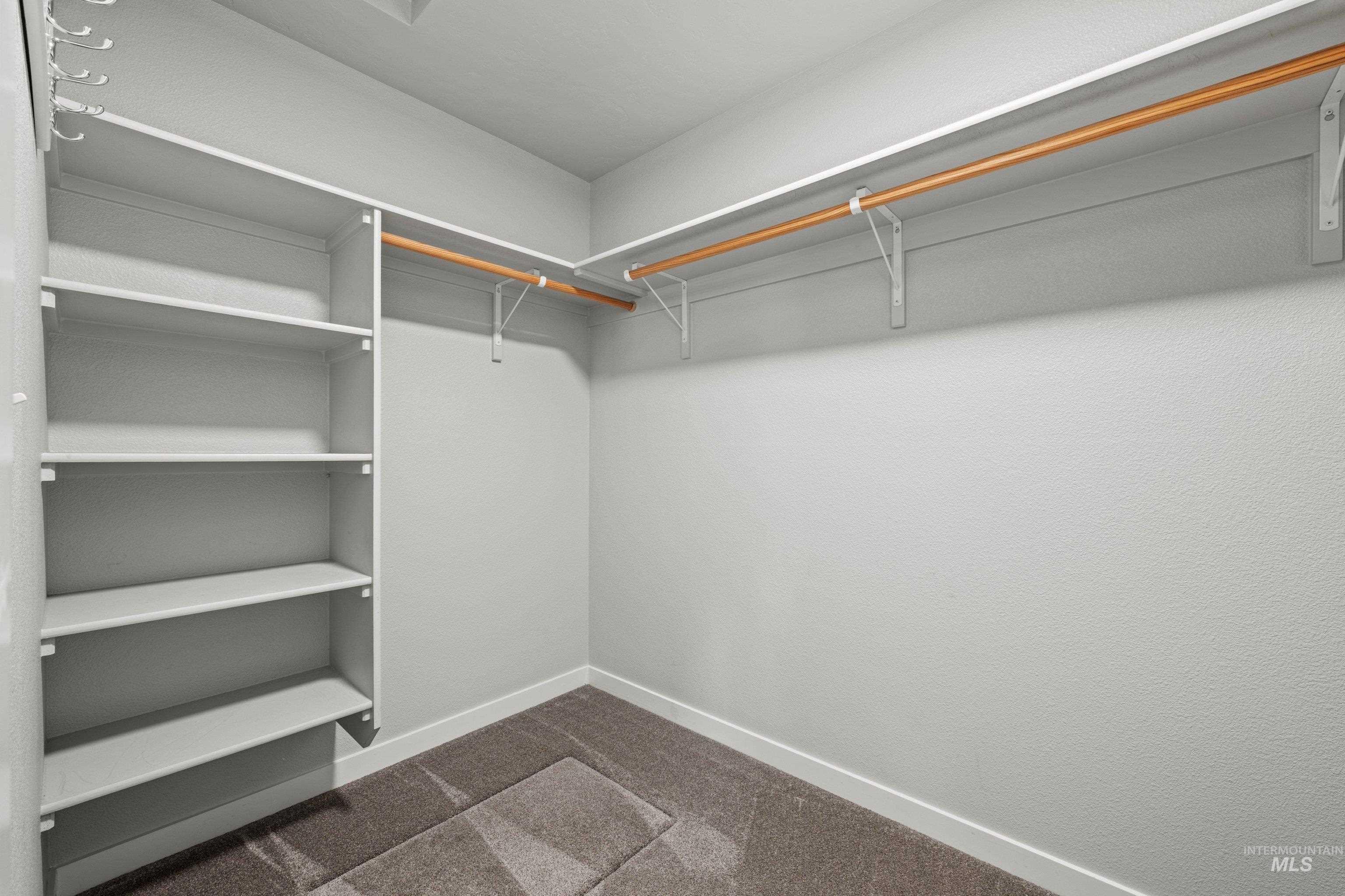 12744 West Fig Street Boise, ID 83713 - Photo 29 of 34 Walk-in closet featuring built-in shelving, two wood-finish hanging rods, and textured wall finish