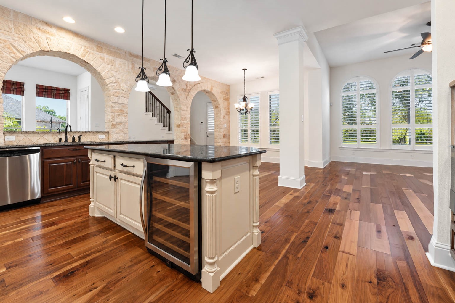 5403 Mesquite Ridge Street Fulshear, TX 77441 - Photo 15 of 42 The kitchen island is a showpiece, pairing crisp white cabinetry with a polished granite top and a built in beverage fridge for effortless entertaining. Three pendant lights hang above it, adding warmth and a designer touch.