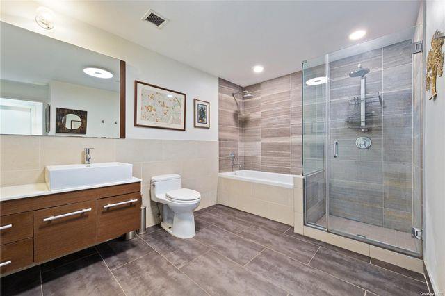 35-40 30th Street, Unit G1 Queens, NY 11106 - Photo 11 of 22 Full bathroom with tile patterned flooring, tile walls, toilet, vanity, and plus walk in shower