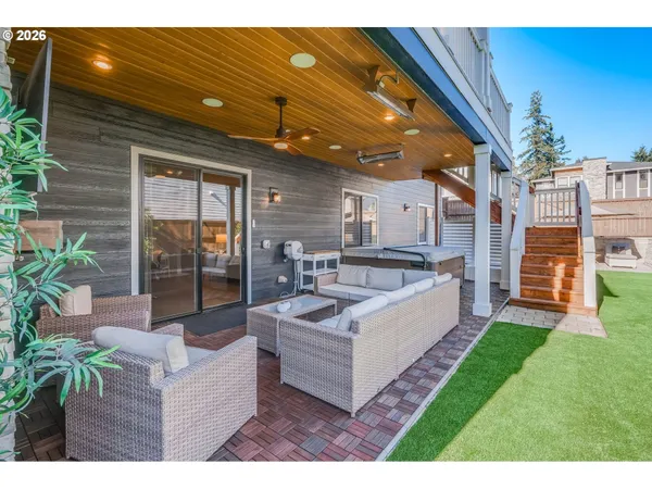 a view of a backyard with couches potted plants and large tree