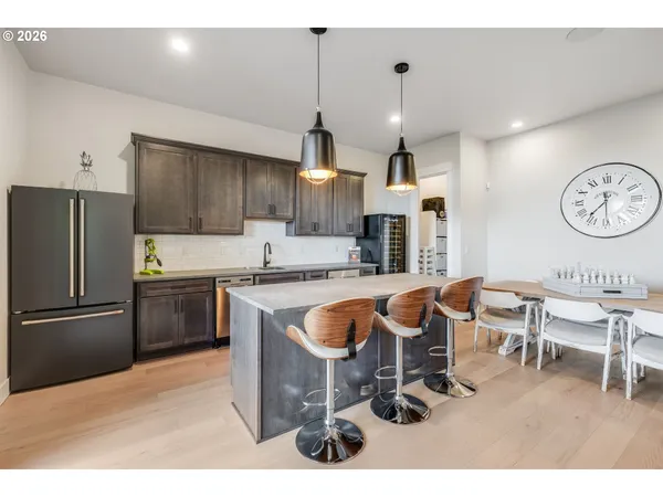 a kitchen with granite countertop a refrigerator a stove a sink and a dining table with wooden floor