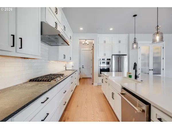 a large kitchen with stainless steel appliances kitchen island a large stove a sink dishwasher and refrigerator with wooden floor
