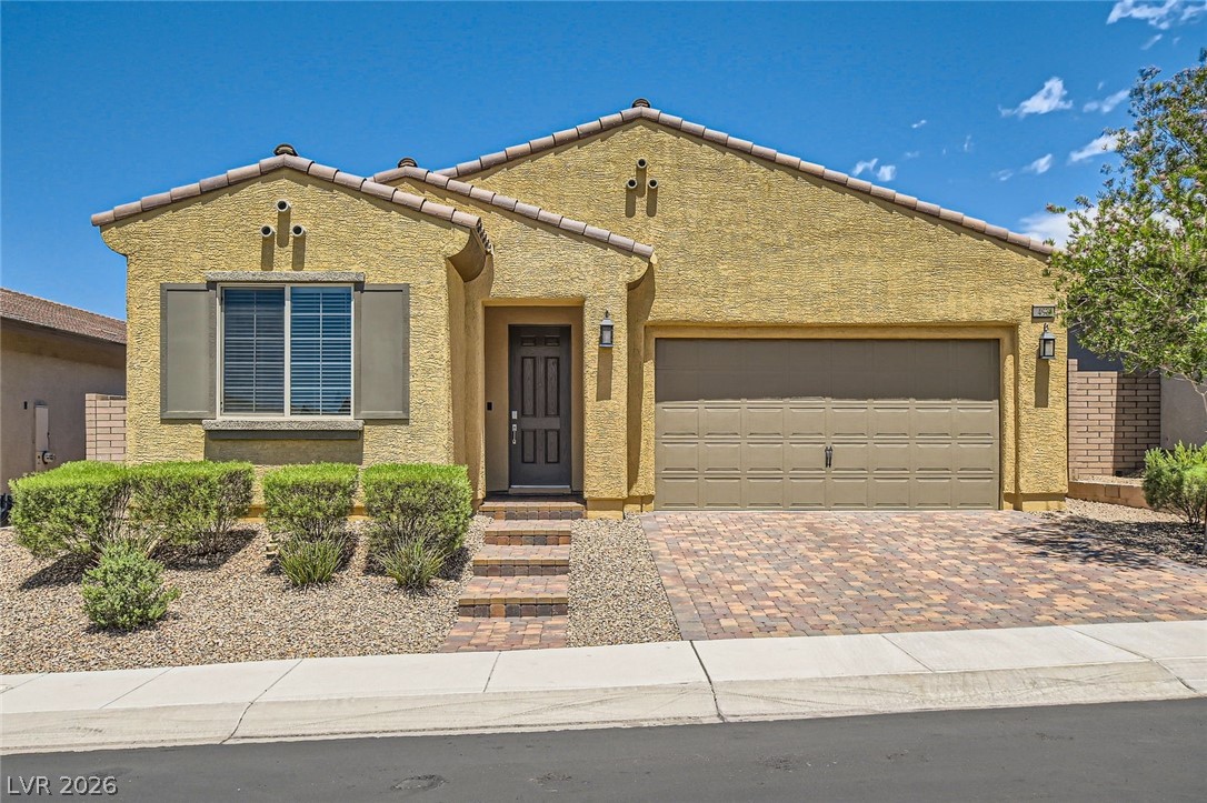 498 Pebble Run Avenue Henderson, NV 89011 - Photo 2 of 47 A well-kept front facade showcasing a single-story home with a brick paver driveway and desert landscaping.